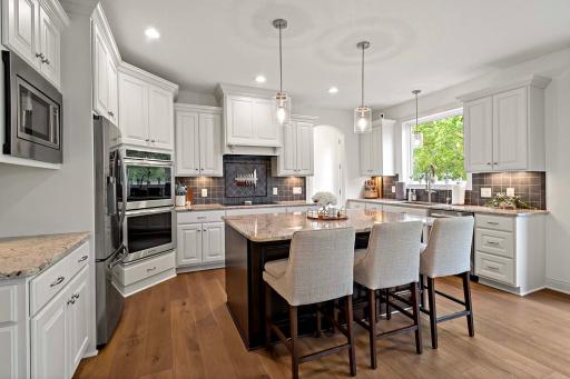 The kitchen boasts high-end appliances and a double oven, centered around a spacious island with seatingâcreating the perfect blend of functionality and casual gathering space.