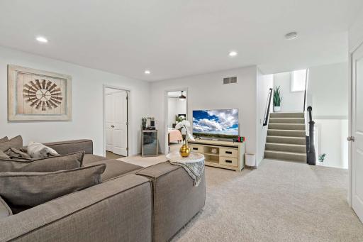An alternative view of the upper loft reveals a spacious, inviting area with stairs leading down to the theater roomâperfectly blending comfort and entertainment in one seamless space.