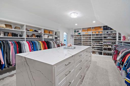 This show-stopping master closet features custom lighting and built-ins throughout, centered around a striking island topped with 3cm Calacatta Laza quartz in a full waterfall design on both ends. A flawless blend of elegance and functionality.