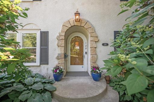 The front door features gorgeous brickwork, surrounded by lush hostas and perennials.