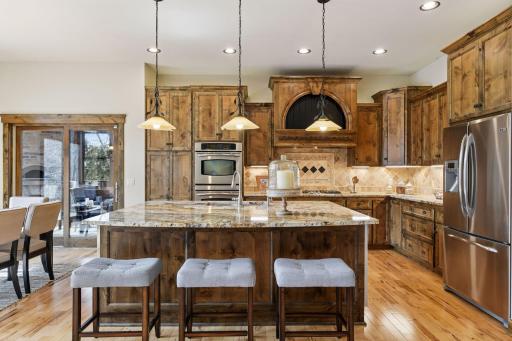 The spacious kitchen features a fantastic center island with ample seating and workspace, complete with a built-in beverage refrigerator and ice maker for added convenience.