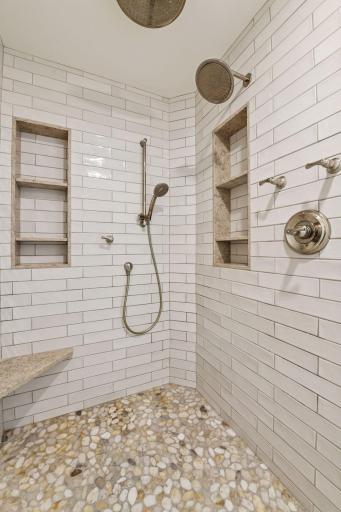 The walk-in shower includes built-in niches and dual showerheads, combining luxury with everyday functionality.