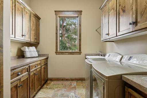 The laundry room is equipped with a washtub, ample cabinetry matches the alder cabinetry in the kitchen plus a coat closet, enhancing both functionality and storage. The flooring was imported from Italy, enhancing the home's Italian-inspired flair.