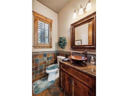 The powder room, a charming half bath, features rich decor and a vessel sink, complemented by attractive floor and wall tiles.