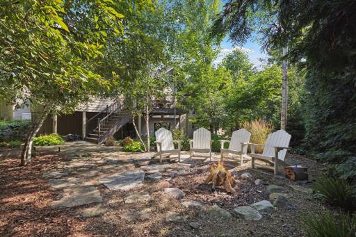 Nestled in the backyard, a cozy firepit beckons, creating an inviting focal point for gatherings and quiet evenings relaxing on Adirondack chairs watching the tranquil fire.