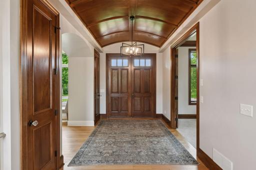 Impressive foyer with arched ceiling lines, hand finished White Oak flooring, and designer curated lighting fixtures greet you