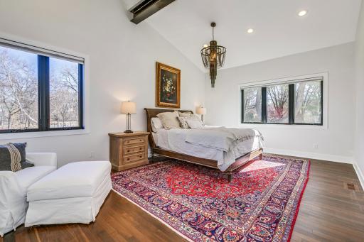 Main level primary bedroom ensuite overlooking the rear yard spaces. Vaulted / beamed ceiling and dramatic lighting keep the industrial / loft feel consistent throughout the home. Large space providing ample room for your bedroom ensemble.