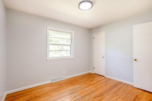 Sun-filled third bedroom with hardwood floors and closet storage.