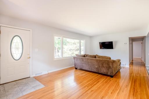 Bright and welcoming living space with large front window, hardwood floors, and fresh paint throughout.