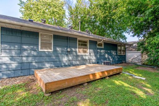 Enjoy the shade and serenity of this tree-lined backyard, complete with a raised wooden deck for outdoor living.
