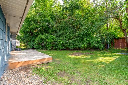 Peaceful backyard view featuring the detached garage, mature trees, and open green space.
