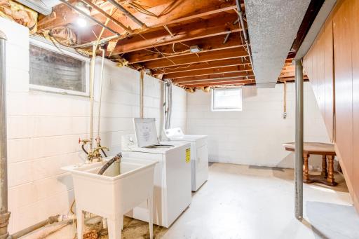 Bright laundry area with washer, dryer, utility sink, and ample space for folding and sorting.