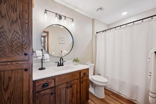 Beautifully updated full bathroom with warm wood cabinetry, matte black fixtures, and modern lighting.