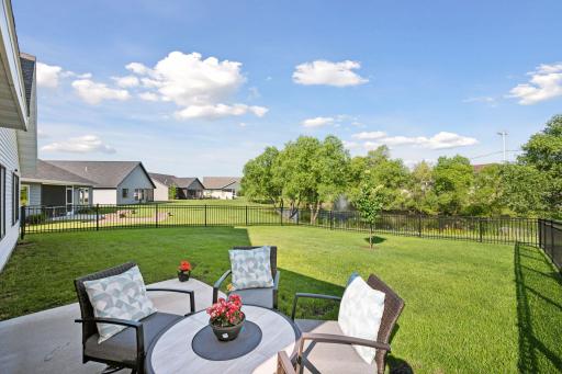Backyard seating area with views of the peaceful pond and mature trees beyond the fence line.