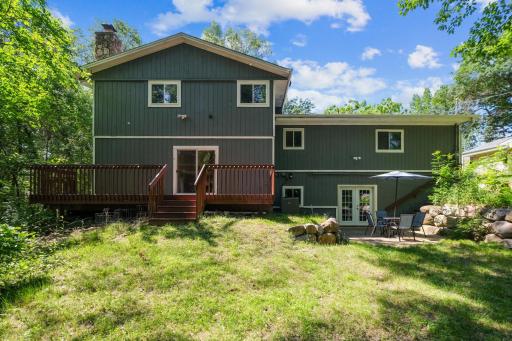 A perspective of the serene back yard featuring an expansive deck and adjacent patio