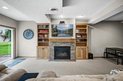 Lower level amusement room with a stone gas fireplace surrounded by built-in's
