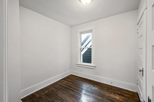 Third upper level bedroom with gleaming hardwood floors and neutral paint.