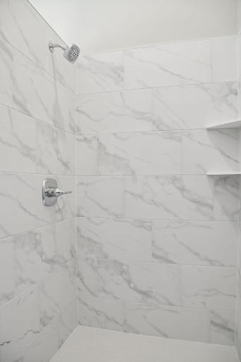 Elegantly tiled walk-in shower in master bath. (Pic of a previous model)
