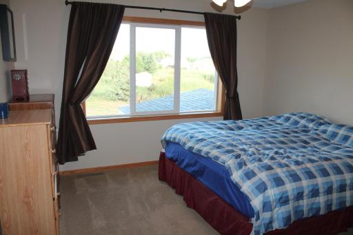 Primary bedroom with a ceiling fan and big window overlooking out to the neighborhood pond.