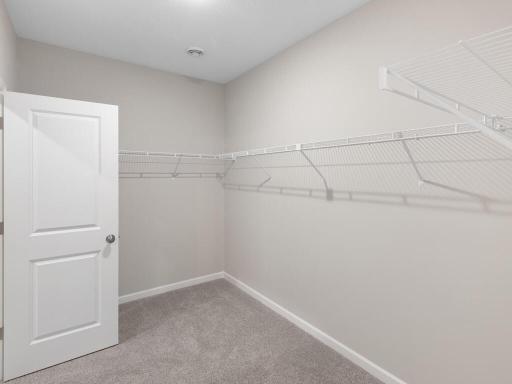 Primary Walk In Closet. Photo taken of another home with similar plan and finishes. Photos and renderings may not depict actual plan, materials, & finishes may vary. All measurements are approximate.