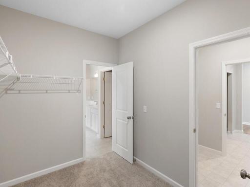 Primary Walk In Closet. Photo taken of another home with similar plan and finishes. Photos and renderings may not depict actual plan, materials, & finishes may vary. All measurements are approximate.