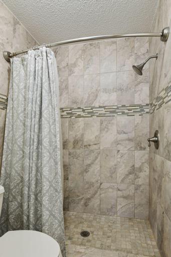 Updated tile surround walk in shower in upper level primary.