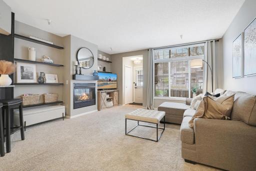 STUNNING bright living room featuring a gas fireplace, entry closet and great views to the patio. New furnace and air conditioning in 2021!
