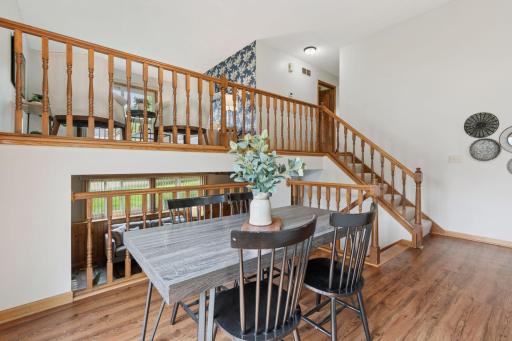 Open-concept dining area with beautiful sightlines to both the upper and lower levels. Rich wood-style LVP flooring and natural light create a warm and connected feel throughout the home.
