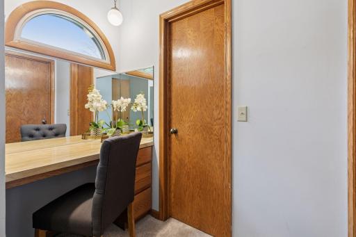 Primary bedroom features soaring vaulted ceilings, brand-new carpet, and a lovely vanity space with mirrors that add both style and practicality.
