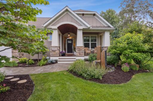 This home features an inviting entryway, lush landscaping, and charming architectural details.