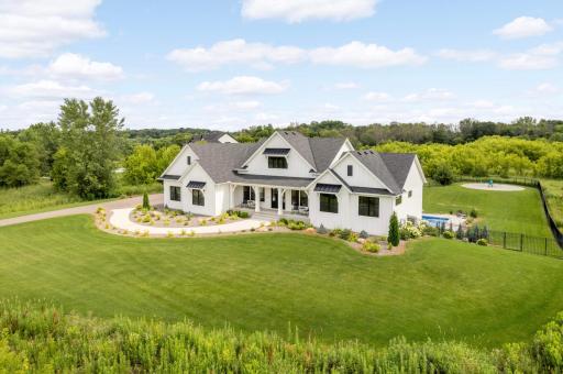 Luxurious modern farmhouse nestled on a private, lush landscaped lot surrounded by natural greenery.