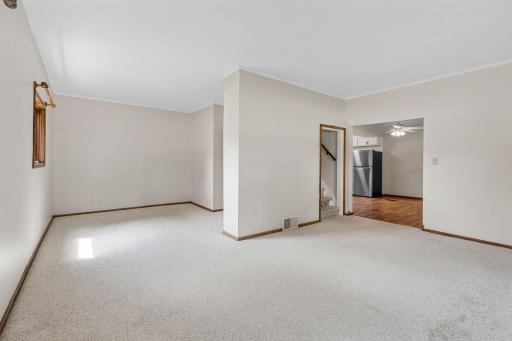 View from corner of living room with den to left and stairs to upper level on right