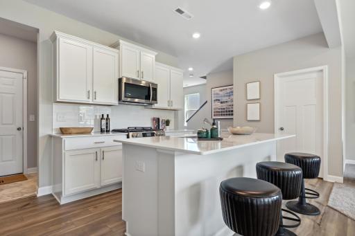 (Photo of decorated model, actual home's finishes will vary) This spacious kitchen features a large island, quartz countertops, recessed lighting, LVP wood floors, stainless appliances and more.