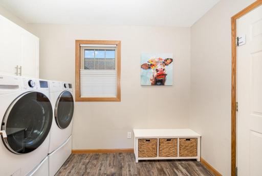 The main floor laundry room features: a utility sink (not pictured), 2 sets of overhead cabinets, and UPDATED: flooring, paint, door hardware & west-facing window. The door on the right leads to the attached 3 car garage. Washer & Dryer NOT included.