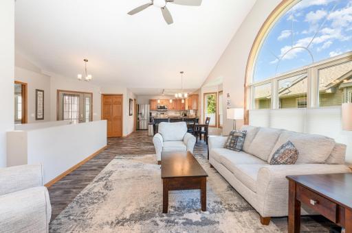 This view of the living room showcases: the open floor plan, and the light-filled room from: the huge windows & soaring vaulted ceiling. Note: spacious, pantry closet to the right of the front door. Original railing removed & 1/2 wall added in 2022.