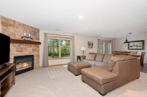 The lower level family room features: a corner, gas fireplace with stone surround & newer mantel; updated: windows & sliding glass door (both overlooking the lush backyard), carpet, paint, and light fixtures.