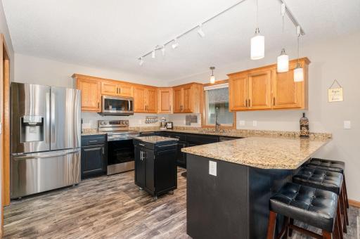 The kitchen features: granite countertops & updated: flooring, paint, cabinet pulls, light fixtures, window, LG stainless steel appliances, and a commercial grade faucet. The base cabinets were painted in 2022 with Behr Premium enamel cabinet paint.