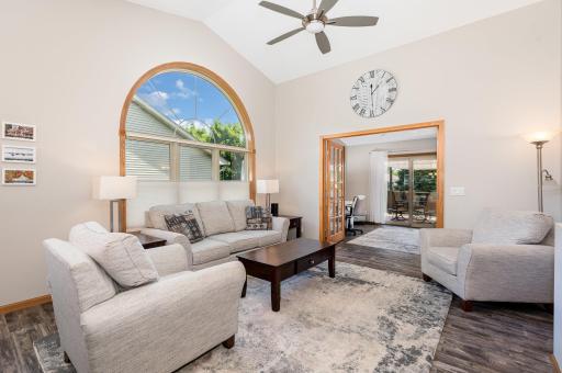 This inviting living room features updated: windows (2020); flooring, paint and ceiling fan (all redone in 2022). This view is looking towards the office/flex room and the outdoor deck.