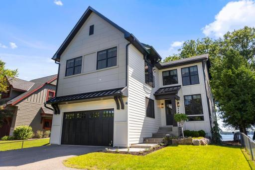 Immaculate 2021 build with bold black accents, charming covered entry, and attached garage—delivering timeless curb appeal just steps from the lake.