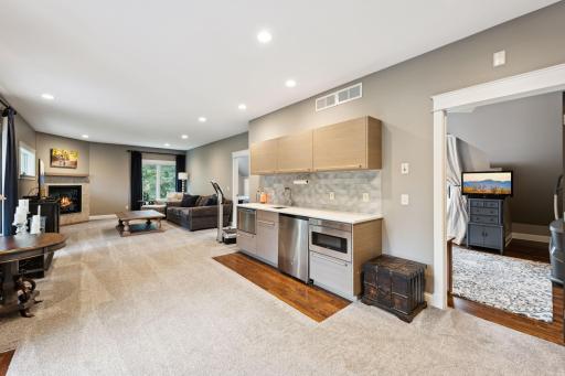 The upper-level wet bar is perfect for entertaining, complete with a sink, microwave, beverage fridge, and dishwasher all seamlessly integrated into a sleek, modern design.