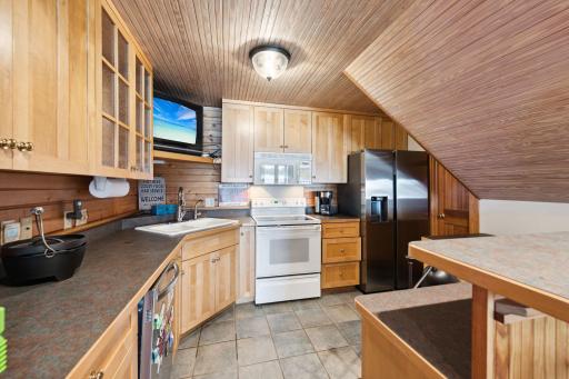The second kitchen in the walk-out lower-level features full-size appliances, including a dish washer, ample cabinetry, and bar seating. Ready for lakeside entertaining or hosting extended stays with ease and convenience.