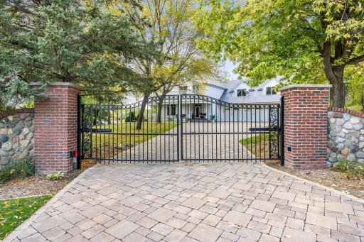 As you arrive, a stately gated entrance framed by brick and stone welcomes you to this exceptional property. The heated paver driveway sets the tone for a home where every detail has been thoughtfully designed and impeccably maintained.