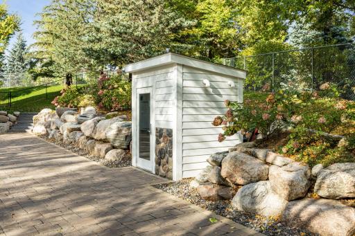 Discreetly tucked into the landscape, this custom utility shed houses the mechanical systems for the heated paver driveway. Thoughtfully designed to blend with the home's exterior, it ensures year-round convenience without compromising aeshetics.