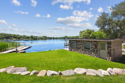 Surrounded by lush lawn and framed with natural stone landscaping, this boathouse provides secure storage for water toys and boating essentials. A rare and highly functional amenity that adds both character and convenience to this extraordinary home.