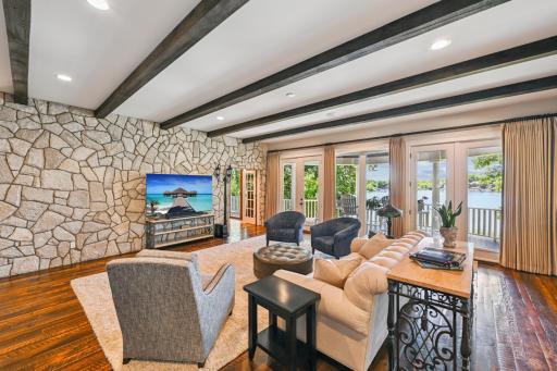 Enjoy stunning lake views from this sun-drenched great room, featuring a full stone accent wall, barn wood flooring, and a wall of picture windows & doors leading to the expansive lakeside covered deck. Porch doors and windows replaced in 2019.