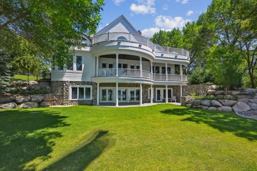 Showcasing timeless architectural elegance, the lakeside of this West Lake Sylvia estate features stunning curved balconies, stacked covered porches, and classic white railings that create seamless indoor-outdoor flow across three levels.