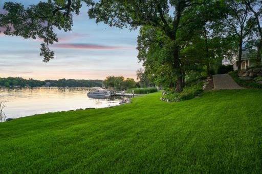 Enjoy a serene, park-like setting with paver pathways, mature trees, boulder-edged gardens, and lush lawn stretching to 385 feet of pristine shoreline on West Lake Sylvia.