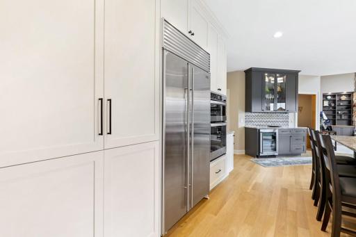From this vantage point, the kitchen showcases impeccable custom cabinetry surrounding premium appliancesâincluding a built-in Sub-Zero refrigerator, a secondary wall oven, and microwaveâall leading toward the inviting and expansive family room.