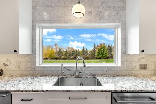 Anchoring the kitchen is a stunning six-foot picture window adorned with elegant marble trim, perfectly positioned over the sink to showcase sweeping panoramic south-facing vistas.