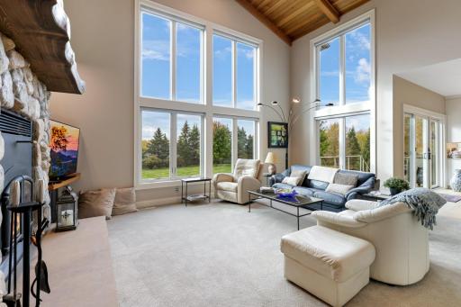 A dramatic two-story wall of windows envelops the family room in radiant natural light, framing expansive south-facing views that offer both beauty and privacy. This architectural highlight creates a sense of grandeur while drawing the outdoors in.